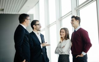Professional business people standing around in informal group chatting
