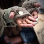 Homeless adult man reaching out for help with change in his hand