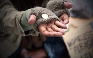 Homeless adult man reaching out for help with change in his hand