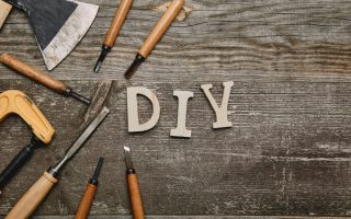 "DIY" written on a wooden table with tools around it