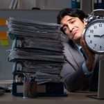 An overworked man at his desk with a close, after working more than 40 hours per week