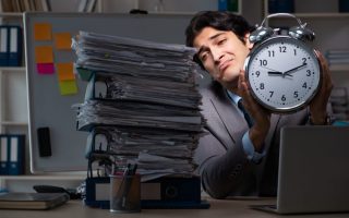 An overworked man at his desk with a close, after working more than 40 hours per week