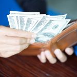 Someone opening their wallet, with a lot of cash that makes them look rich