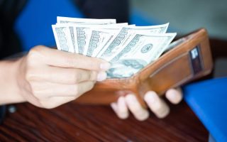 Someone opening their wallet, with a lot of cash that makes them look rich