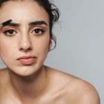 A woman putting makeup on, knowing that certain faces are seen as more trustworthy