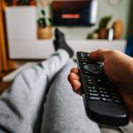 Someone on a couch binge watching a show on Netflix