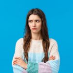 A woman looking guilty in front of a blue background