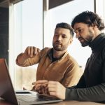 Two co-workers sitting side by side at a computer