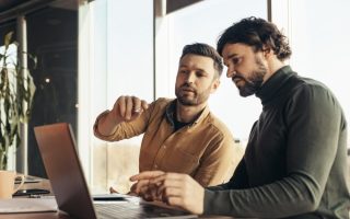 Two co-workers sitting side by side at a computer