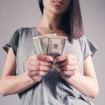 A young woman holding cash that she accepted as financial help from her parents