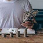 Someone counting money and attempting to avoid personal finance threats from inside their household