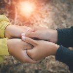 Two female friends holding hands and creating a strong bond that all people want