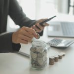 An American dropping coins into a jar, to give them personal finance skills