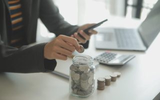 An American dropping coins into a jar, to give them personal finance skills