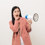 A woman speaking out loud through a megaphone, amplifying her voice