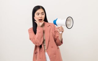 A woman speaking out loud through a megaphone, amplifying her voice