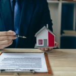 A landlord with a model of a home and a lease agreement