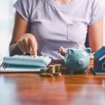 Someone with a piggy bank, calculator, and coins working on family rules about money