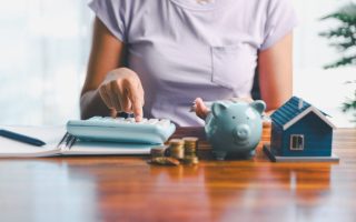 Someone with a piggy bank, calculator, and coins working on family rules about money