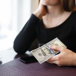 A woman holding money and thinking of a shortcut to make more