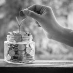 A young person dropping a coin into a jar to secure financial future