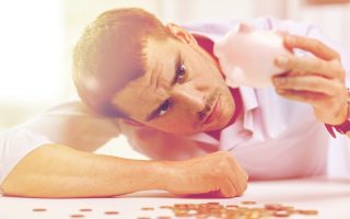 A man with a piggy bank hiding his debt from his partner