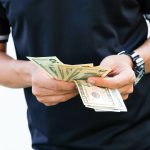 A man holding cash, a budget trick that sounds smart but actually isn't.