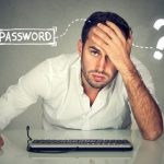 An annoyed man in front of his computer, having forgot his internet password