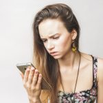 A woman looking upset at a text message