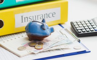 A desk with insurance paperwork and binders. There are types of insurance that are useless these days
