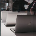 A group of Apple laptops. Apple is a tech company whose CEO has been fined but still runs the business.