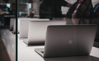 A group of Apple laptops. Apple is a tech company whose CEO has been fined but still runs the business.