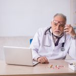 A doctor with a bunch of pills on his desk
