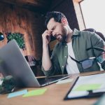 A man looking exhausted and distressed at his workplace