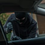 A thief breaking into a car